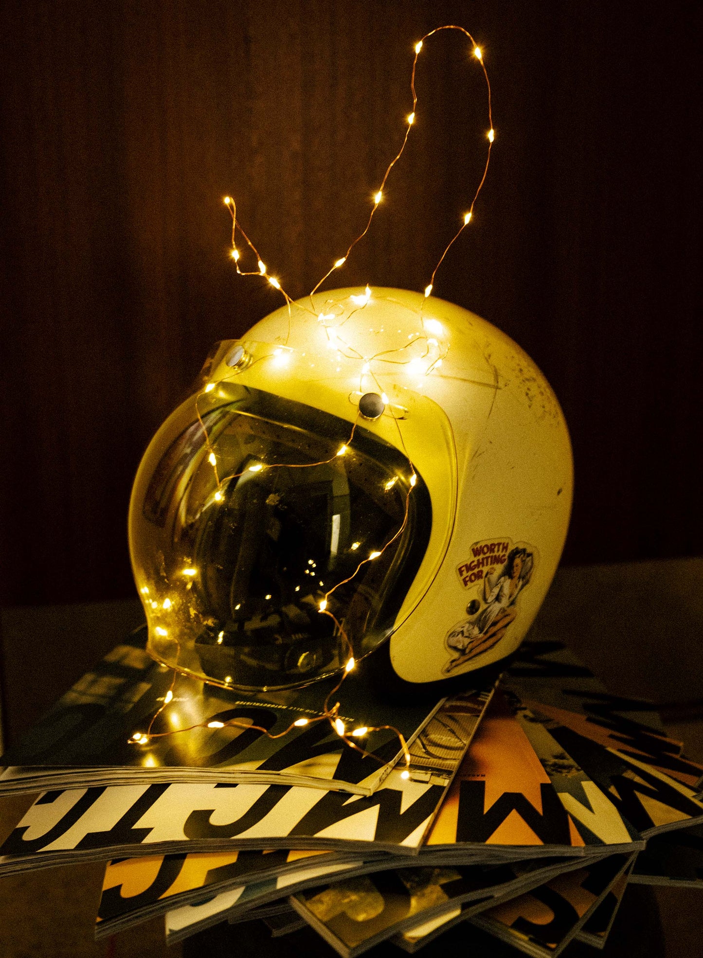 Retro motorcykelhjelm udsmykket med lyskæde placeret ovenpå MCTC-magasiner