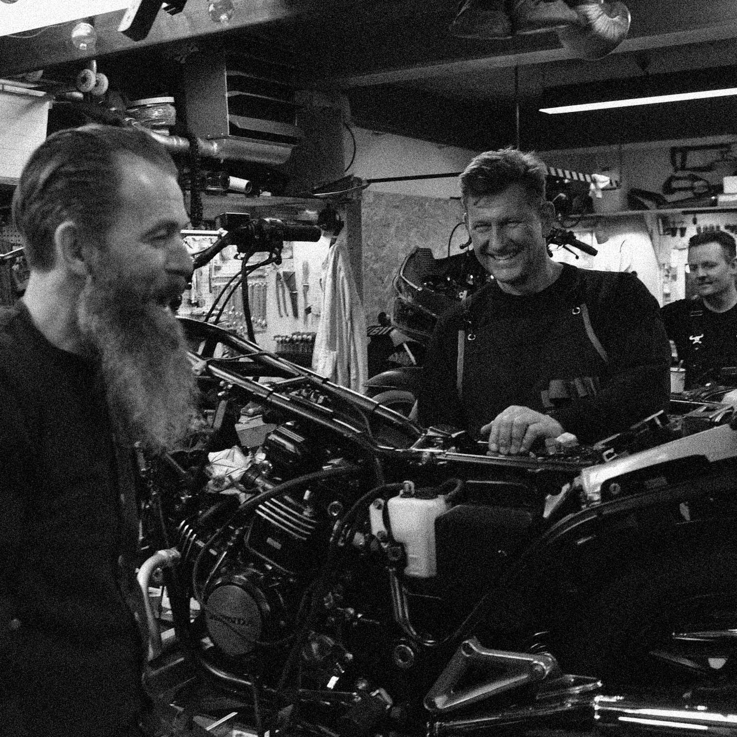 Motorcyklister i værkstedsfællesskab med gammel motorcykel, der er ved at blive stand i stand