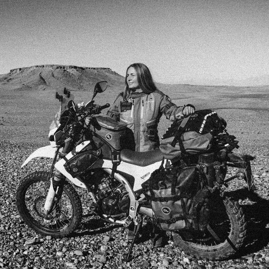 Eventyrer Henriette Thiim står bagved sin motorcykel i ørkenen